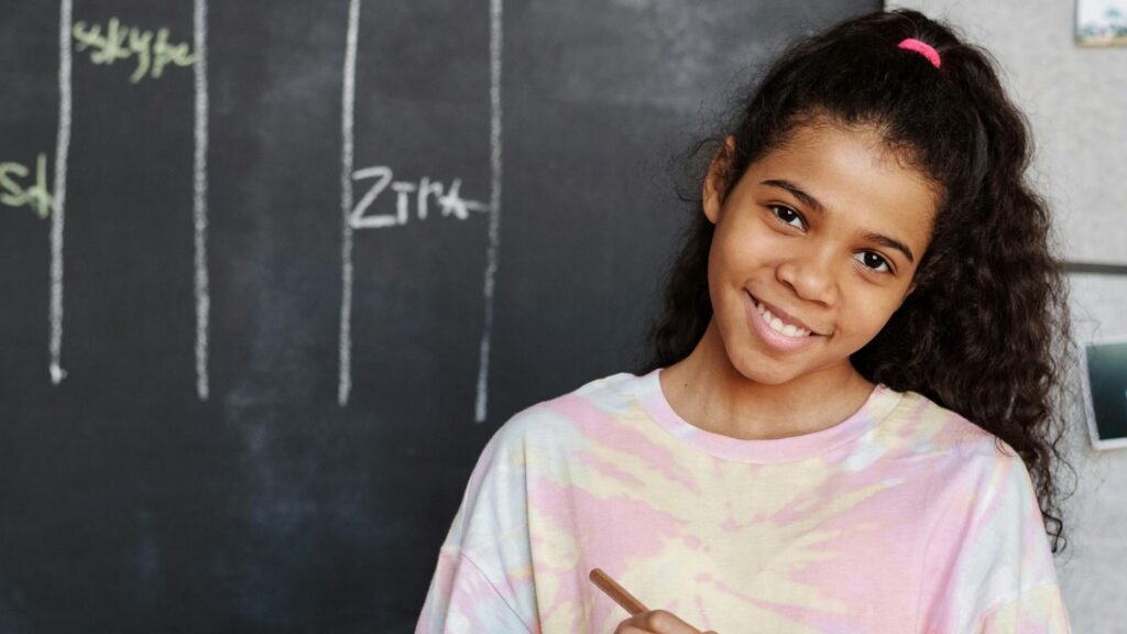 A child in smiling in classroom; SoundEd therapy for learning challenges