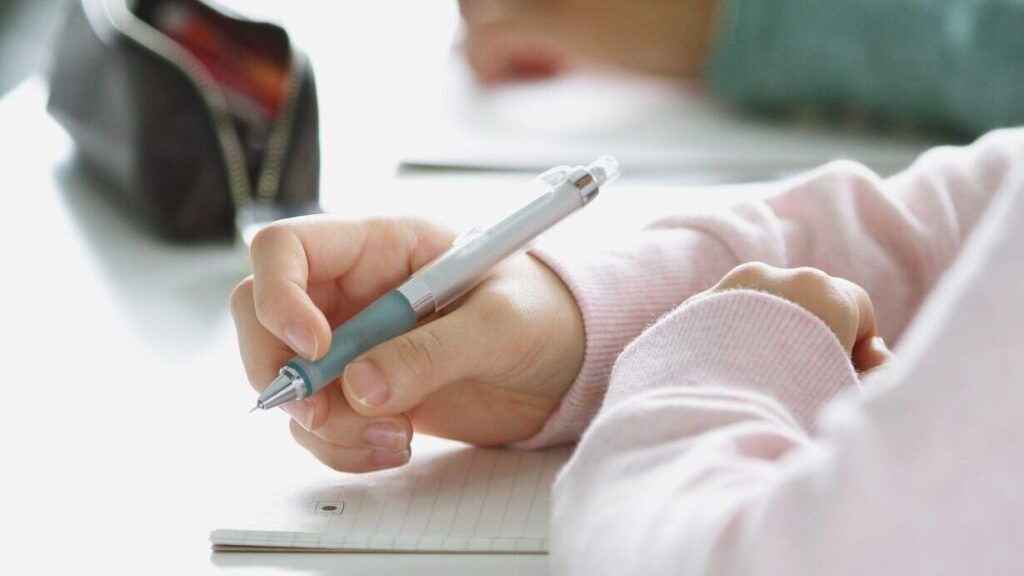 A child holding a pen in class; SoundEd therapy for learning evaluations